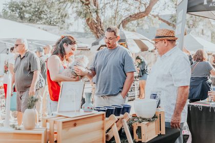 Crowd of shoppers at a Dreamers Markets pop-up in golden afternoon light