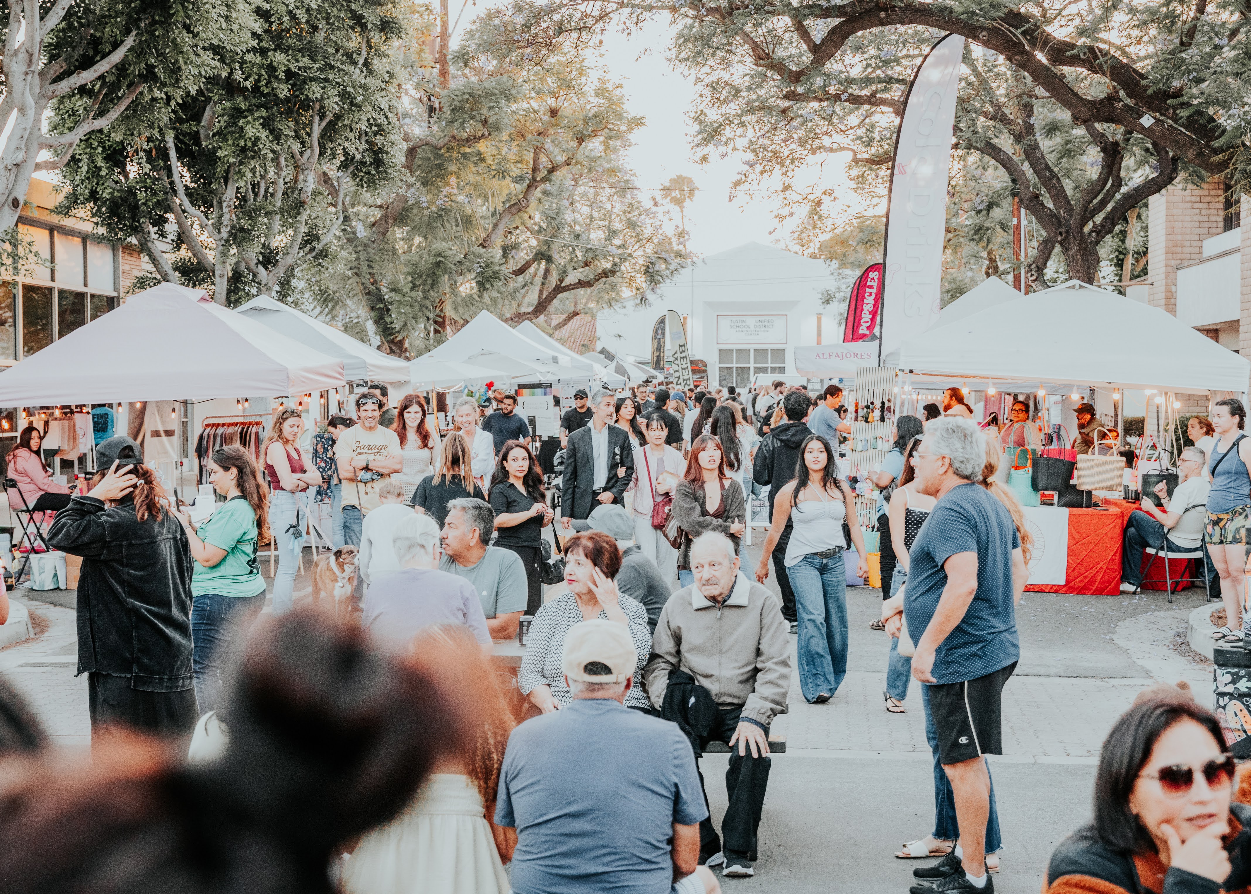 Crowd of shoppers at a Dreamers Markets pop-up vendor market in Tustin in golden afternoon light