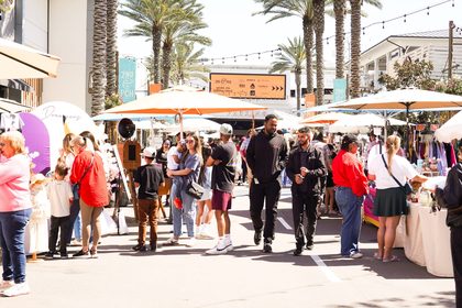 Shoppers strolling along a palm-lined mainstreet at a Dreamers Markets pop-up