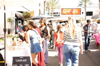 Crowd around a permanent jewelry vendor booth at a Dreamers Markets pop-up