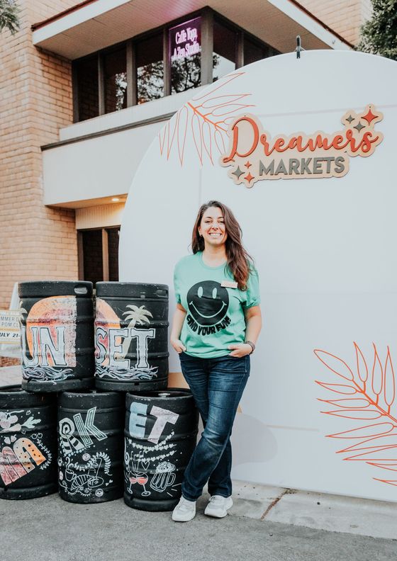 Deniz Karmona standing by the Dreamers Markets sign